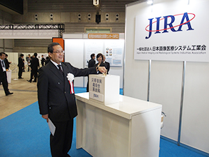 会場内に熊本地震の募金箱を急遽設置　募金する小松・JIRA会長